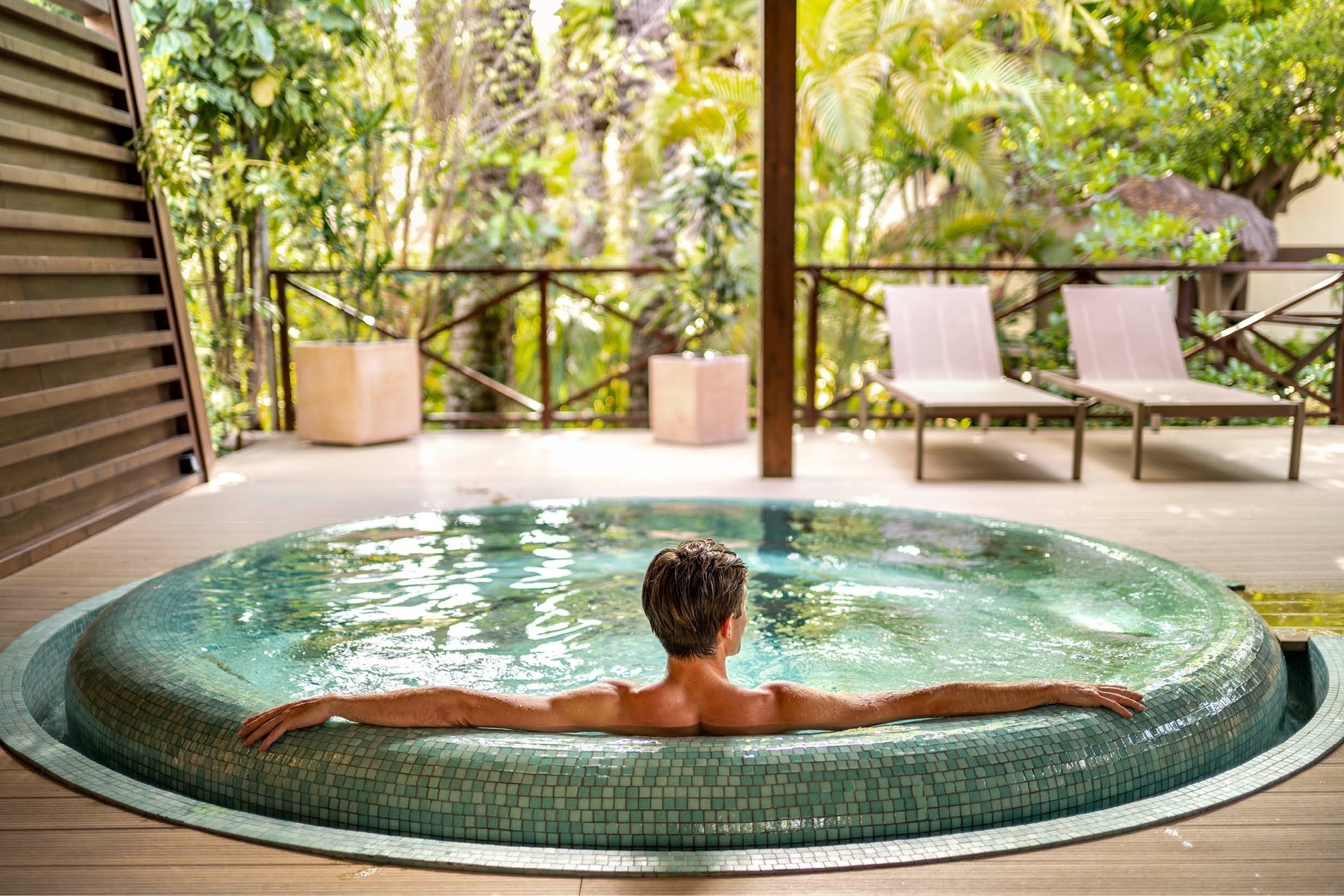 a man sits in a hot tub with his arms outstretched