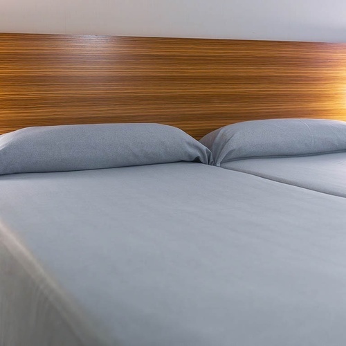 una habitación con dos camas y una cabecera de madera