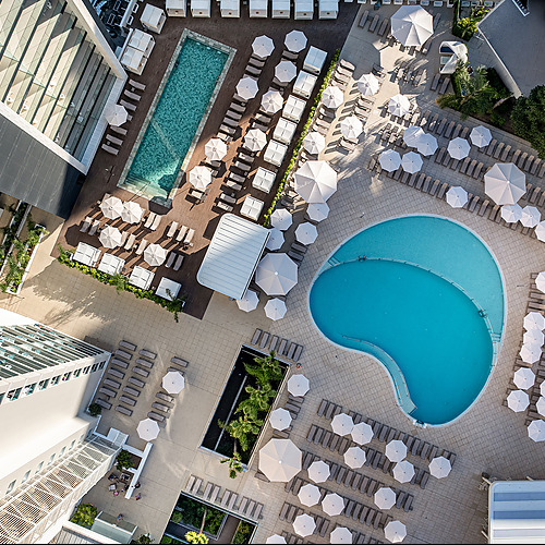 Vista aérea de piscina y camastros de hotel, perfecto paraPort Hotels: Corporativa