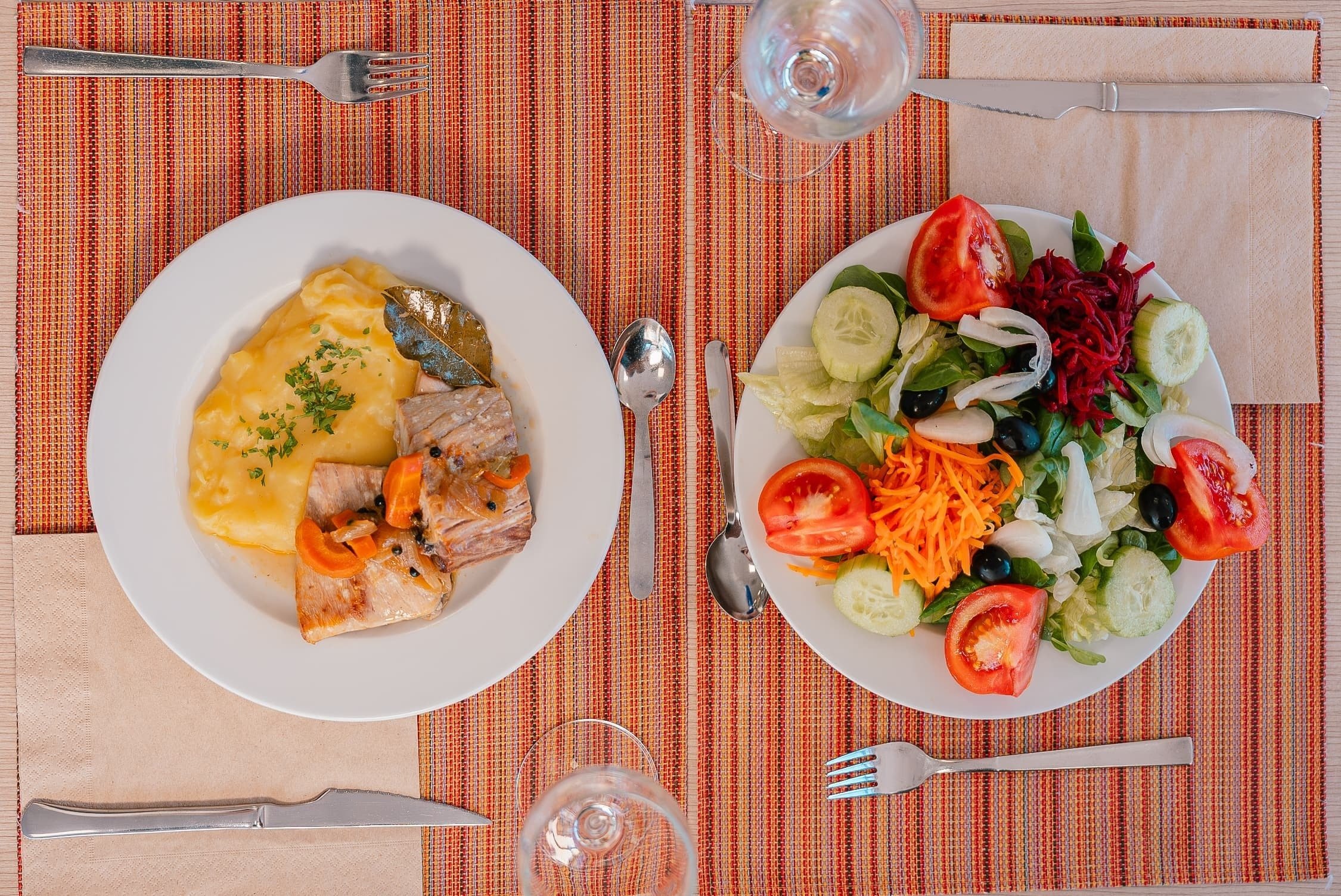 two plates of food on a table including a salad