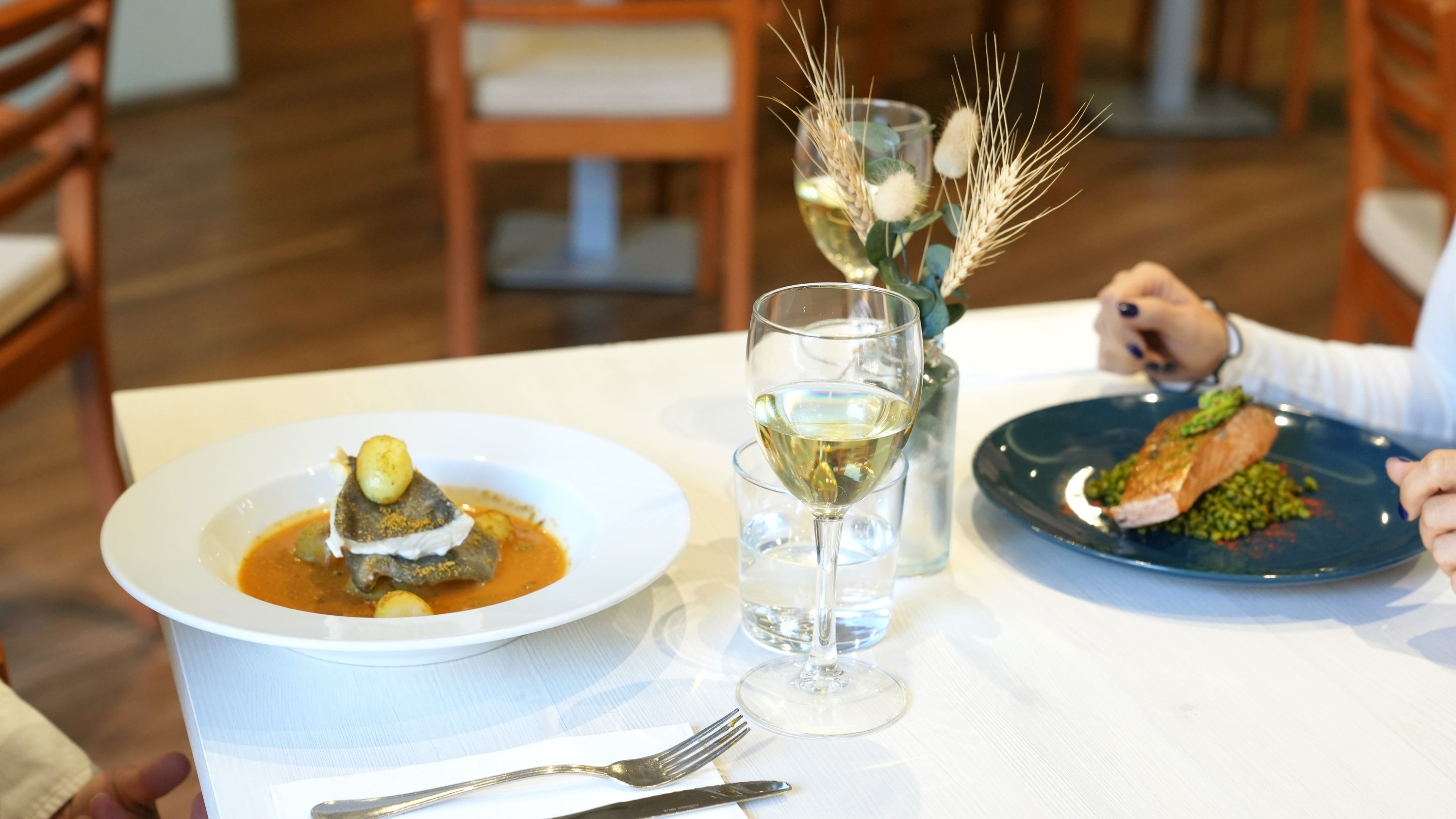 two plates of food and two glasses of wine on a table