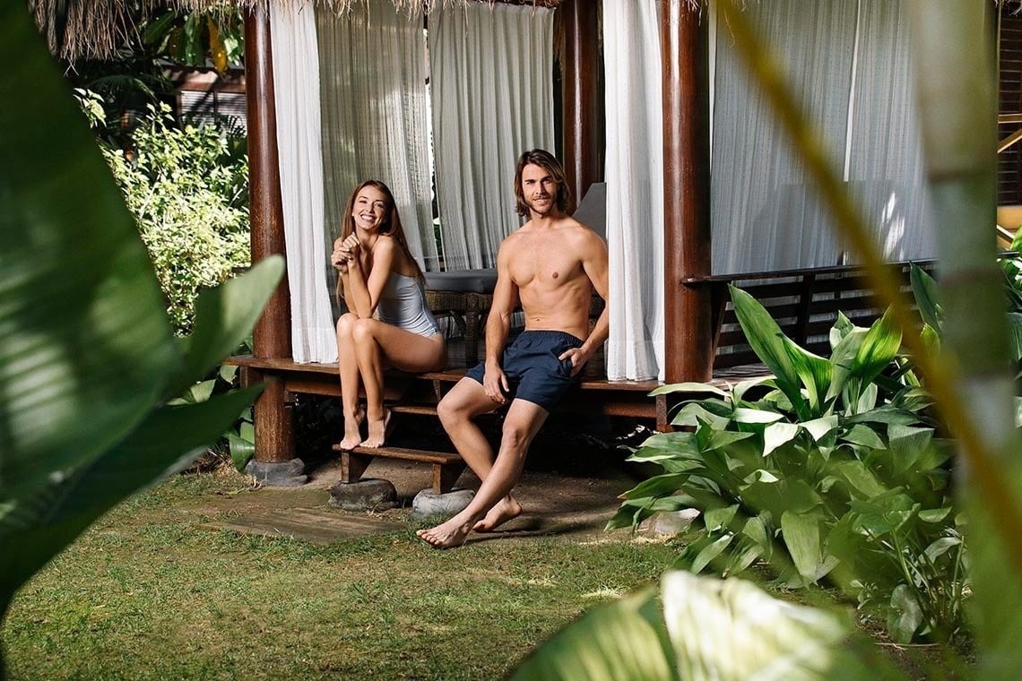 a man and a woman are sitting on a bench in front of a gazebo .