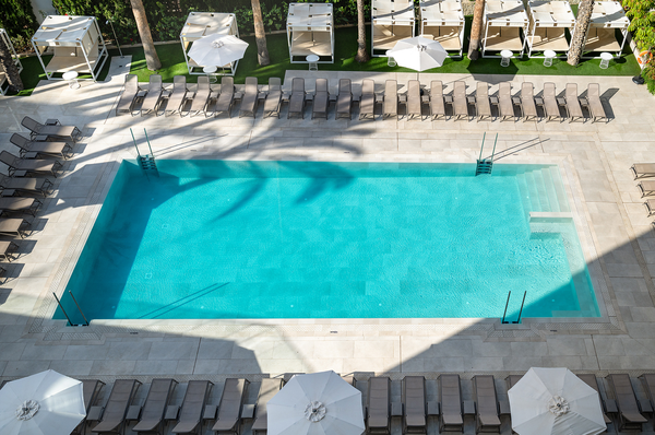 una piscina rodeada de sillas y sombrillas en un hotel