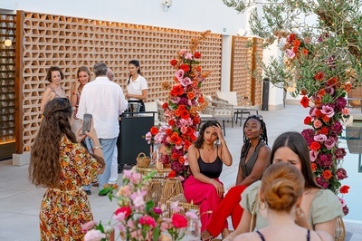 a woman taking a picture of a group of people with flowers in the background - 