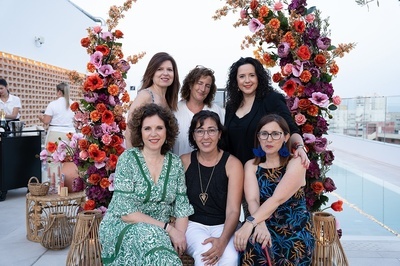 a group of women posing for a picture in front of flowers - 