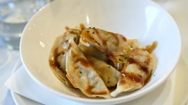 a white bowl filled with fried dumplings and sauce