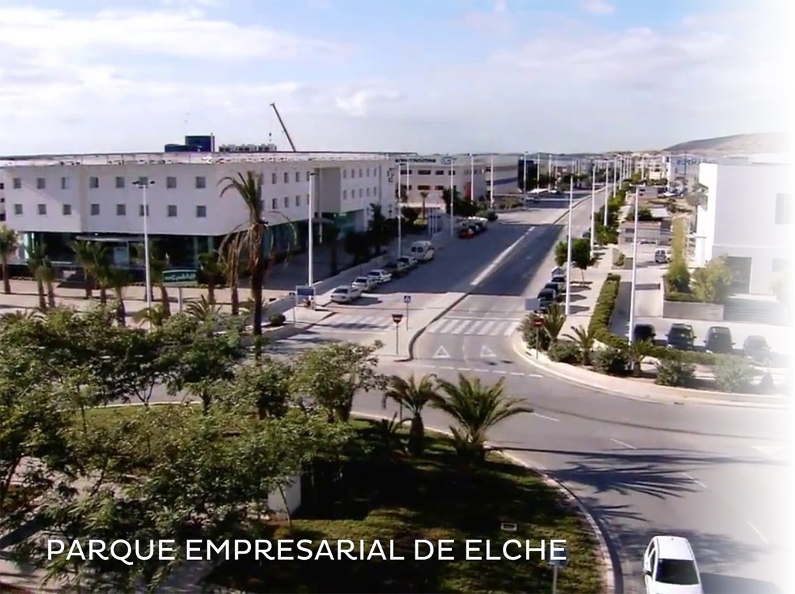 un grupo de personas camina por una calle frente a un gran edificio blanco .