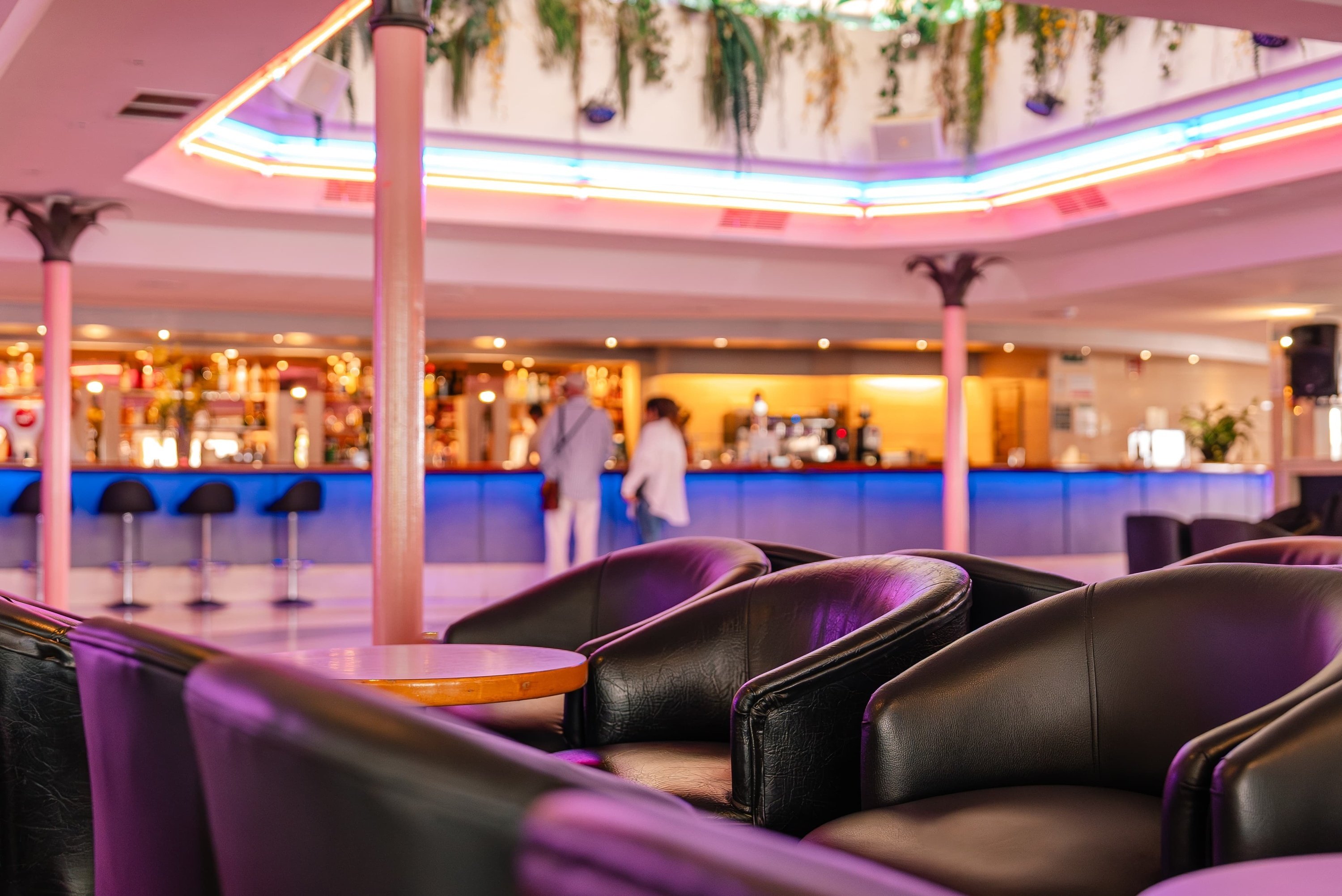 a restaurant with purple chairs and a blue bar