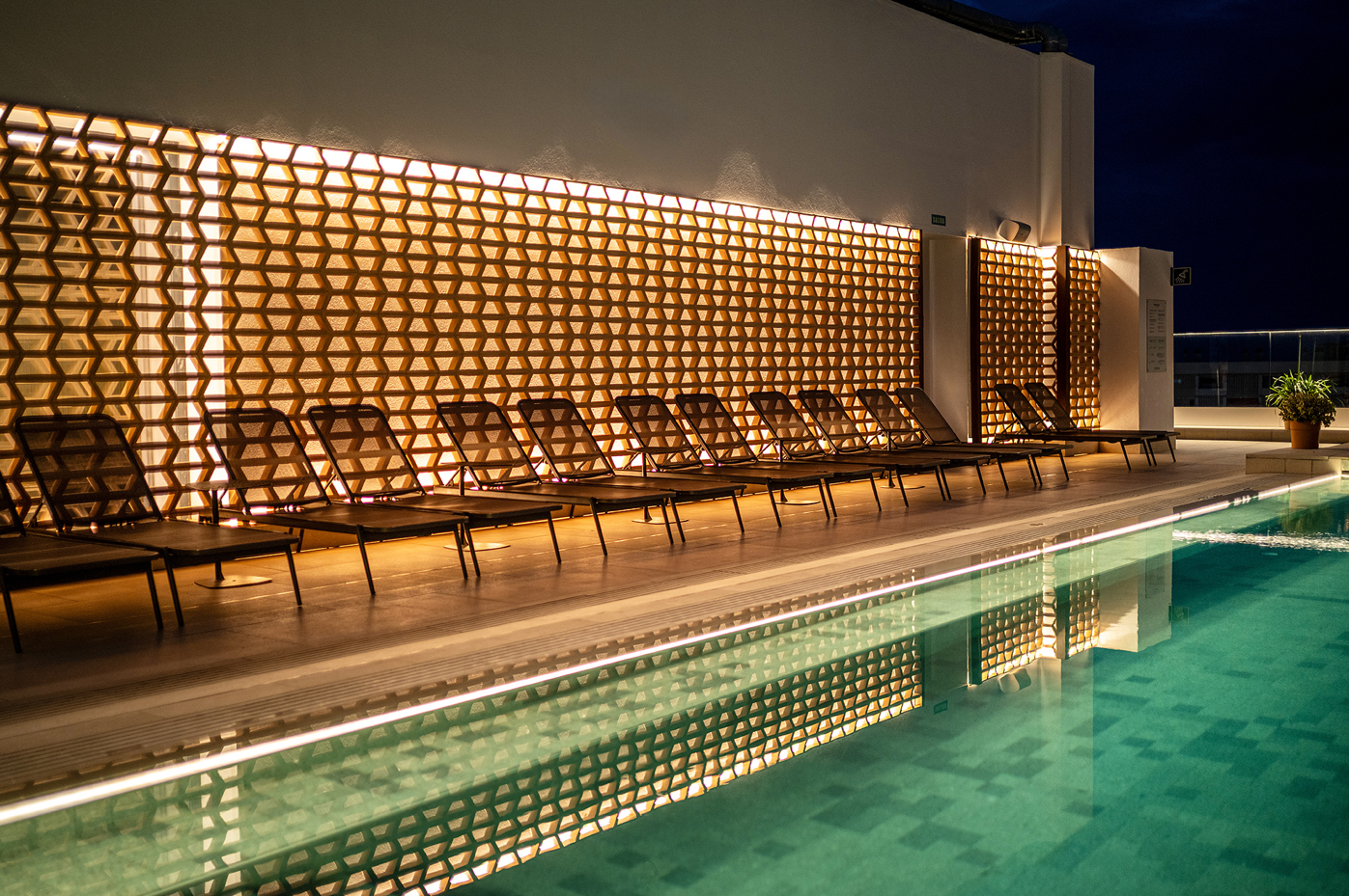 una fila de sillas junto a una piscina en la noche