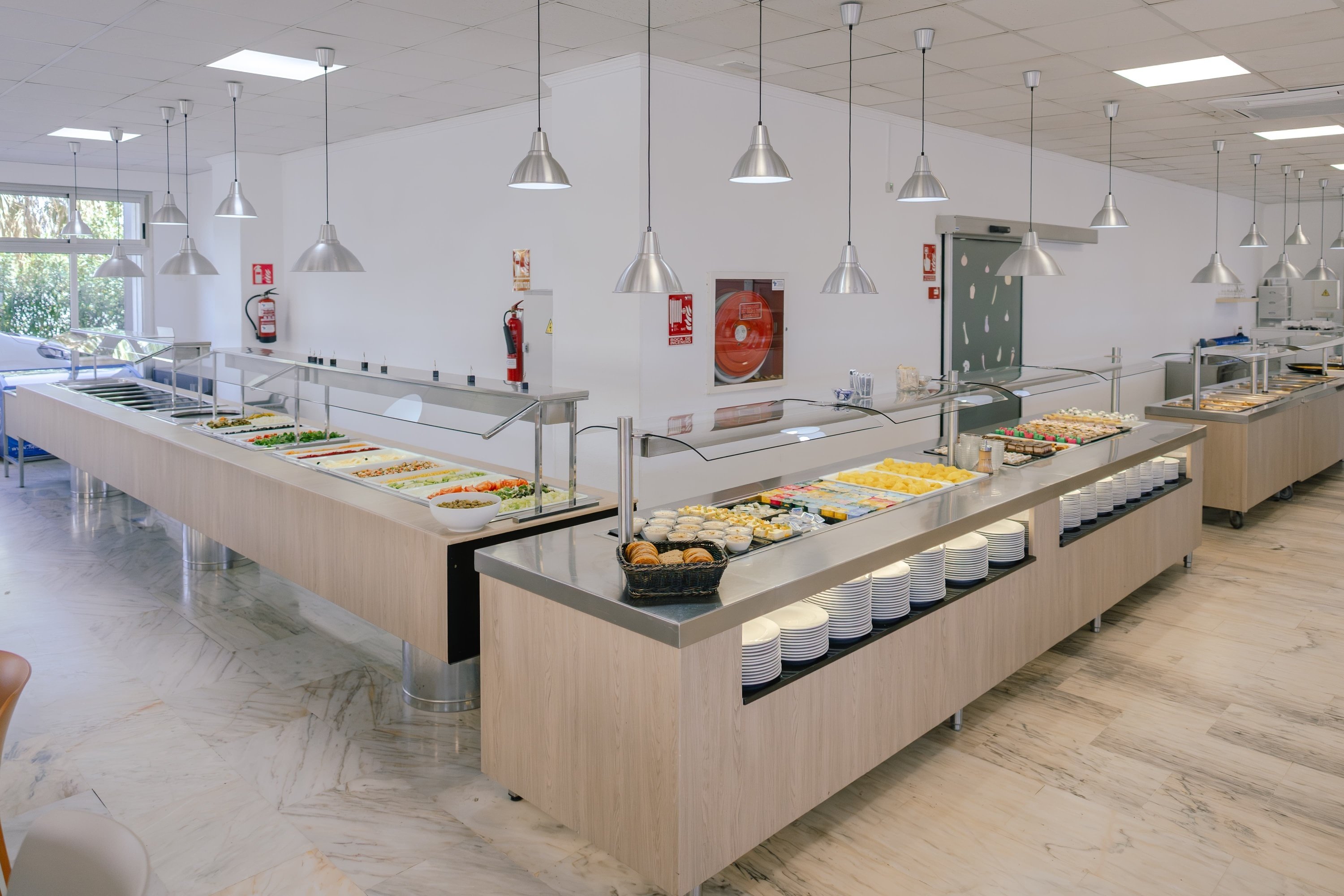 a buffet line in a restaurant with a fire extinguisher on the wall