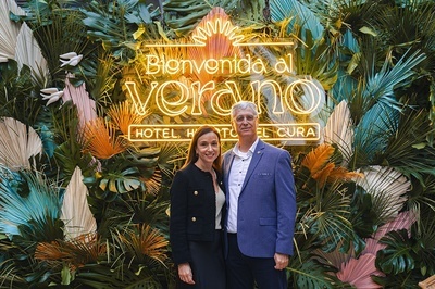 a man and woman standing in front of a sign that says bienvenido al verano - 