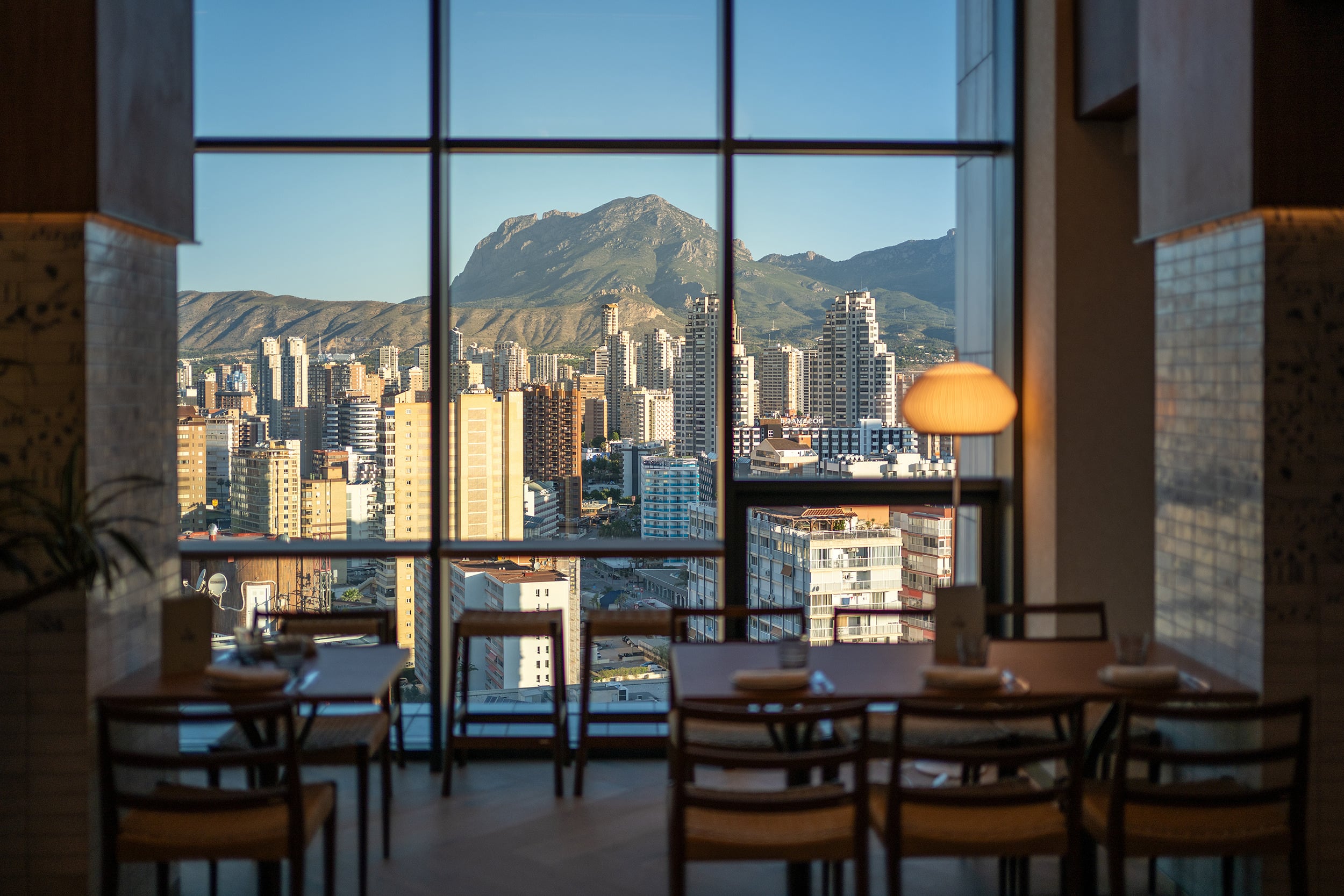 Vista desde restaurante de hotel con mesas y vista a la ciudad y montaña Port Hotels: Corporativa