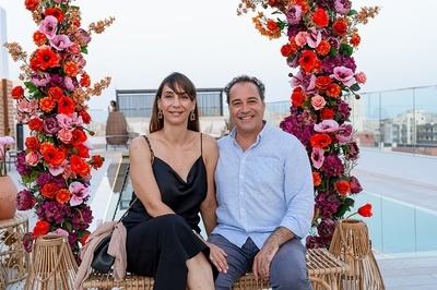 a man and a woman are posing for a picture in front of flowers - 