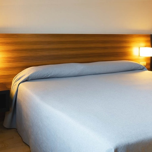 una cama con una colcha azul y una cabecera de madera