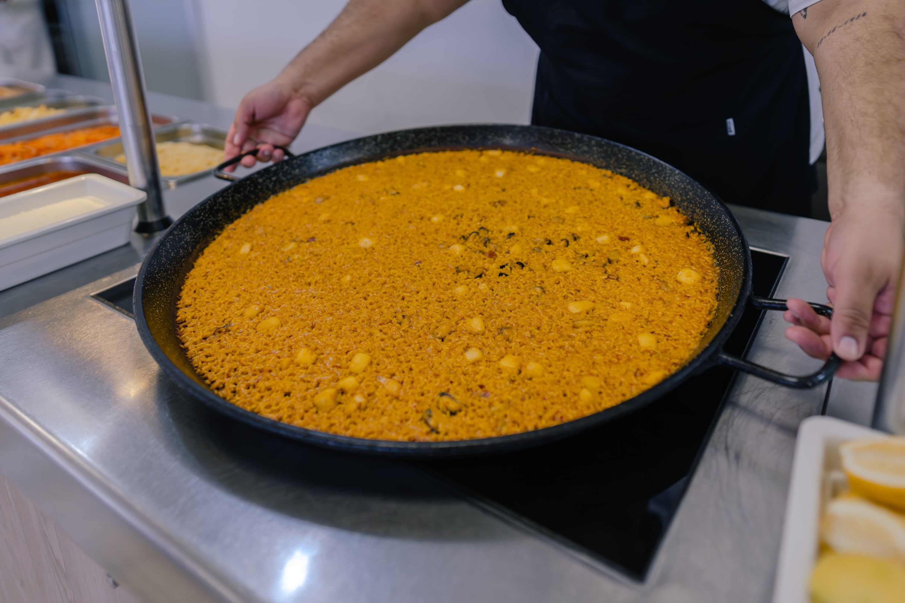 a person with a tattoo on their arm holding a pan of food