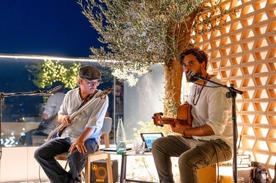 a man playing a guitar next to a man singing into a microphone - 