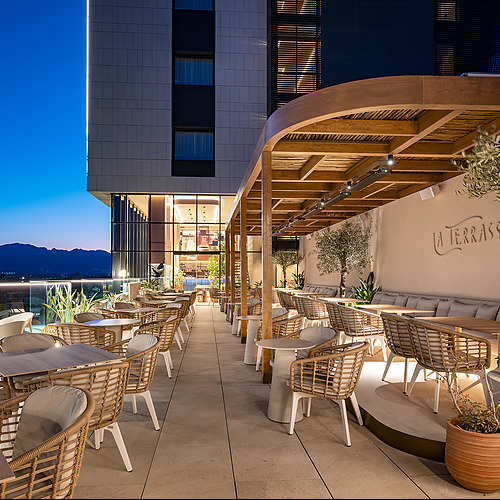 Terraza de hotel con asientos al aire libre, mesas y vistas nocturnas de Port Hotels: Corporativa.