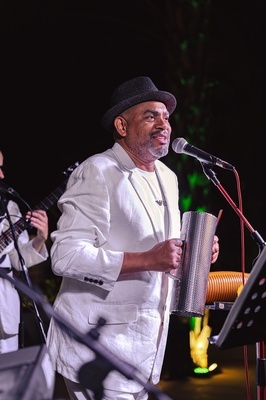 a man in a white suit is singing into a microphone - 