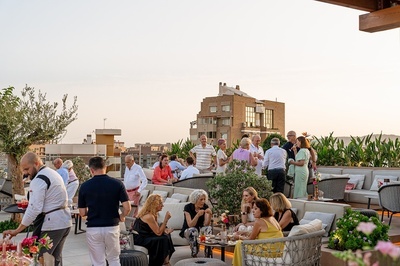 a group of people gathered on a patio with a building in the background - 