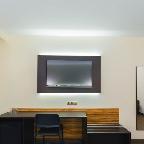 una habitación con un escritorio y una televisión en la pared