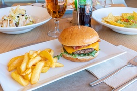 un plato blanco con una hamburguesa y papas fritas y una botella de coca cola