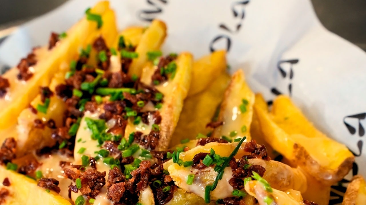 un primer plano de un plato de papas fritas con queso y bacon