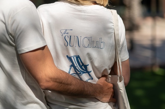 un hombre abraza a una mujer con una camiseta blanca que dice el club del sol