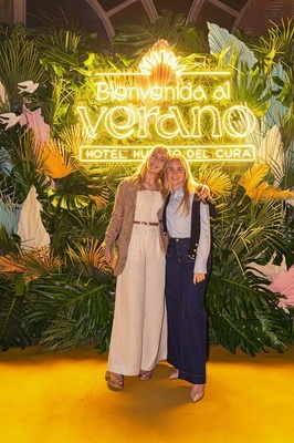 two women pose in front of a sign that says bienvenido al verano - 