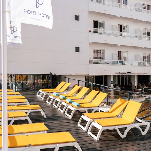 a row of yellow lounge chairs in front of a building that says port hotels