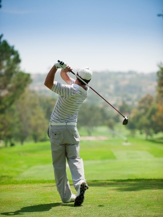 a man swings a golf club on a golf course