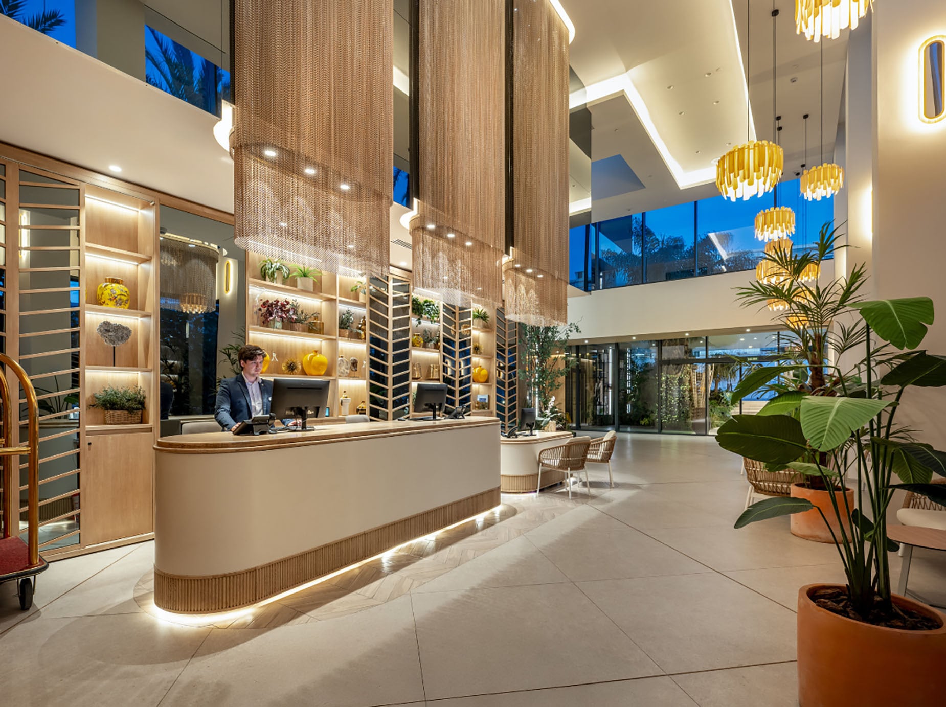 Recepção elegante de hotel com decoração moderna e plantas verdes, ideal para Hotel Port Alicante City & Beach | Port Hotels | Web Oficial.