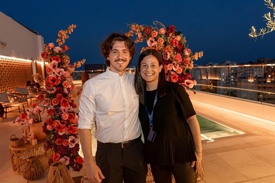 un hombre y una mujer posan para una foto frente a un arco de flores - 