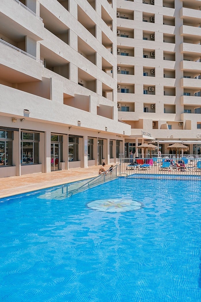 a large swimming pool with a hotel in the background