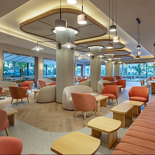 Port Hotels: Corporativa: Sofás naranjas y mesas de madera en sala lounge moderna del hotel.
