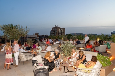 un grupo de personas están sentadas en sillas y mesas en un restaurante al aire libre - 