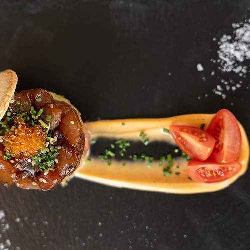 un plato de comida con tomates y una galleta encima
