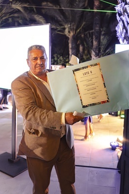 a man holding a piece of paper that says lote 6 - 