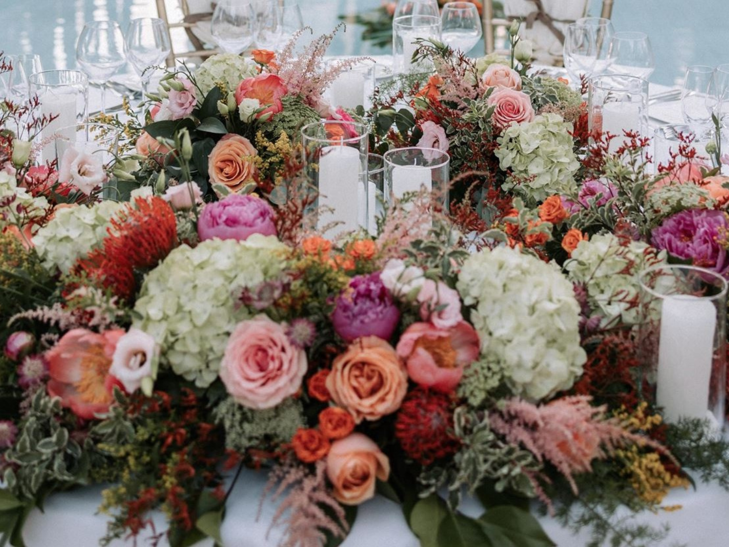 una mesa decorada con flores y velas junto a una piscina