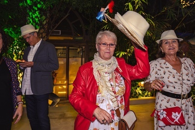 a woman in a red jacket holds up her hat - 