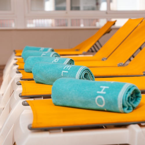 una fila de tumbonas amarillas con toallas azules que dicen relajarse
