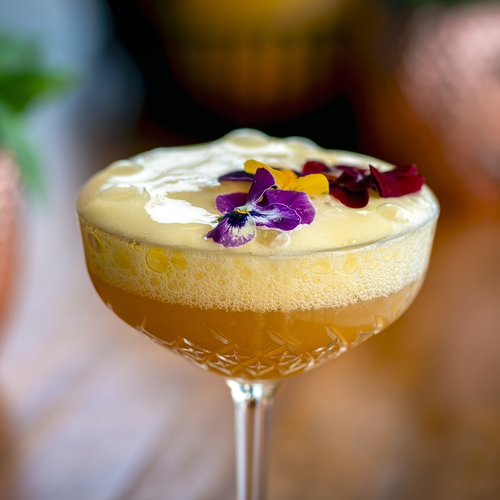 un cóctel en una copa con una flor morada encima