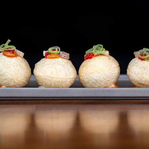 tres bolas de comida están en un plato sobre una mesa de madera