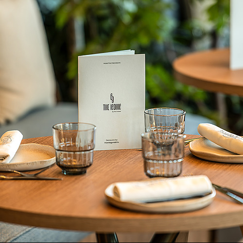 Mesa elegante con menú y servilleta enrollada en el restaurante Port Hotels: Corporativa.
