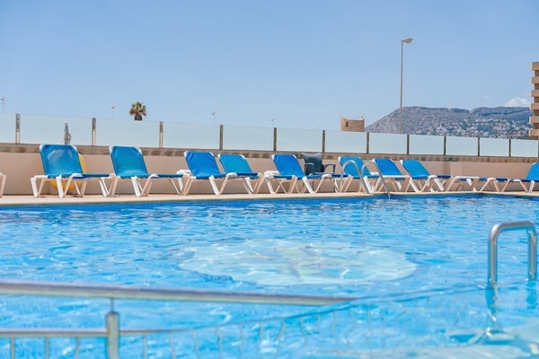 a swimming pool with blue chairs and a mountain in the background