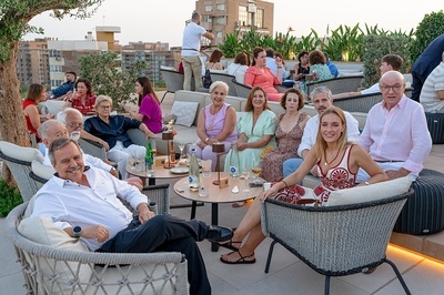 un grupo de personas se sienta en sillas y mesas en una terraza - 