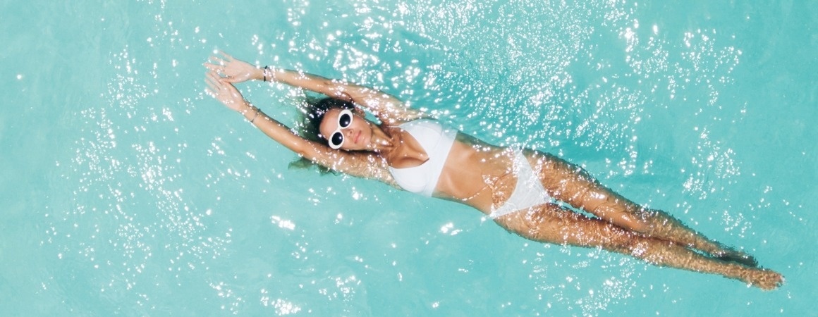 una mujer nadando en una piscina con gafas de sol