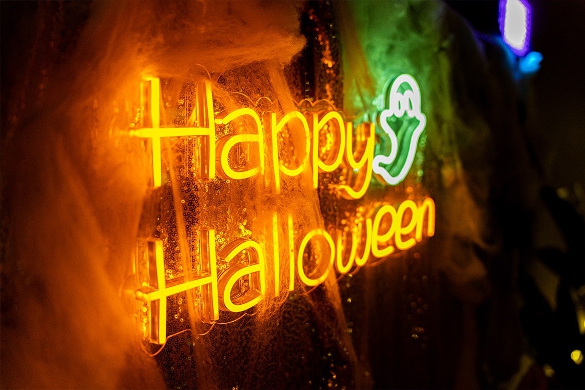 a neon sign that says happy halloween on it