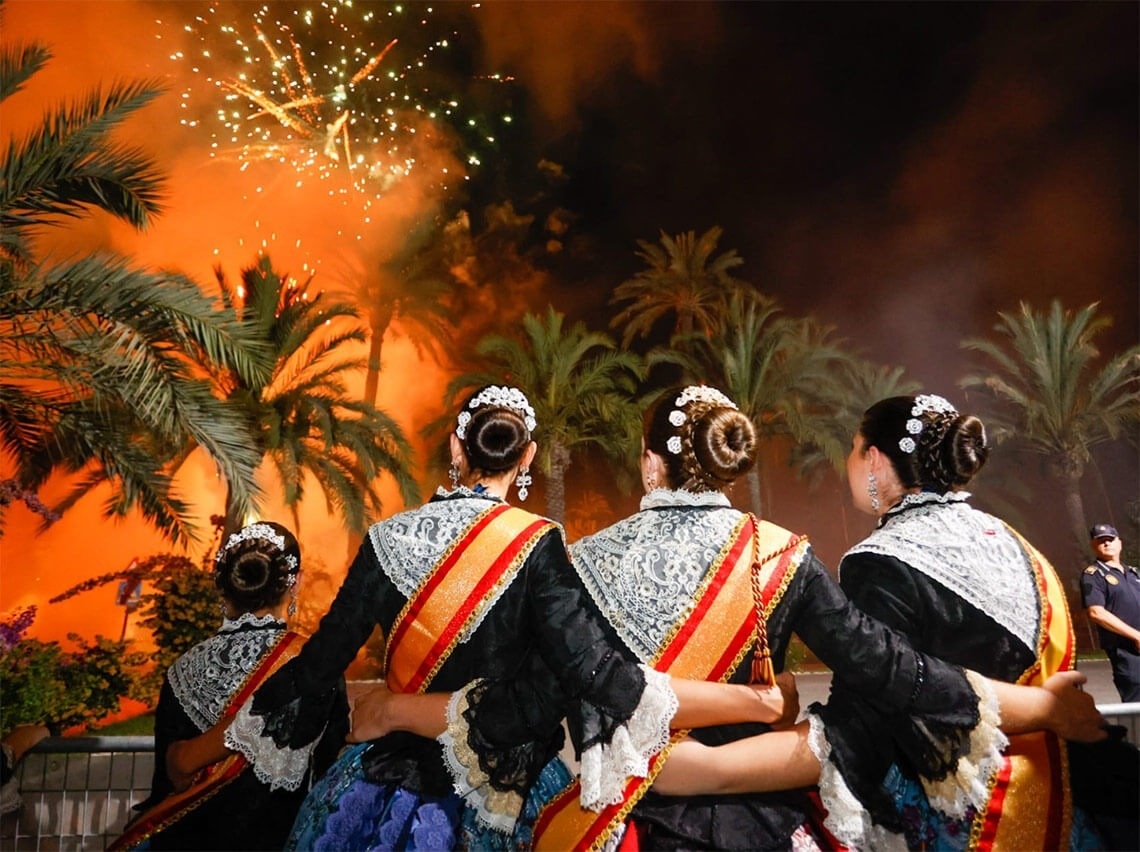 un grupo de mujeres en vestidos tradicionales miran los fuegos artificiales