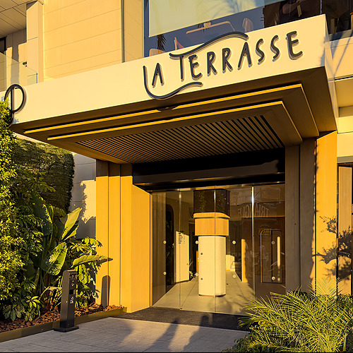 Port Hotels: Corporativa La Terrasse: Entrada de hotel moderna con vegetación exuberante y luz dorada.
