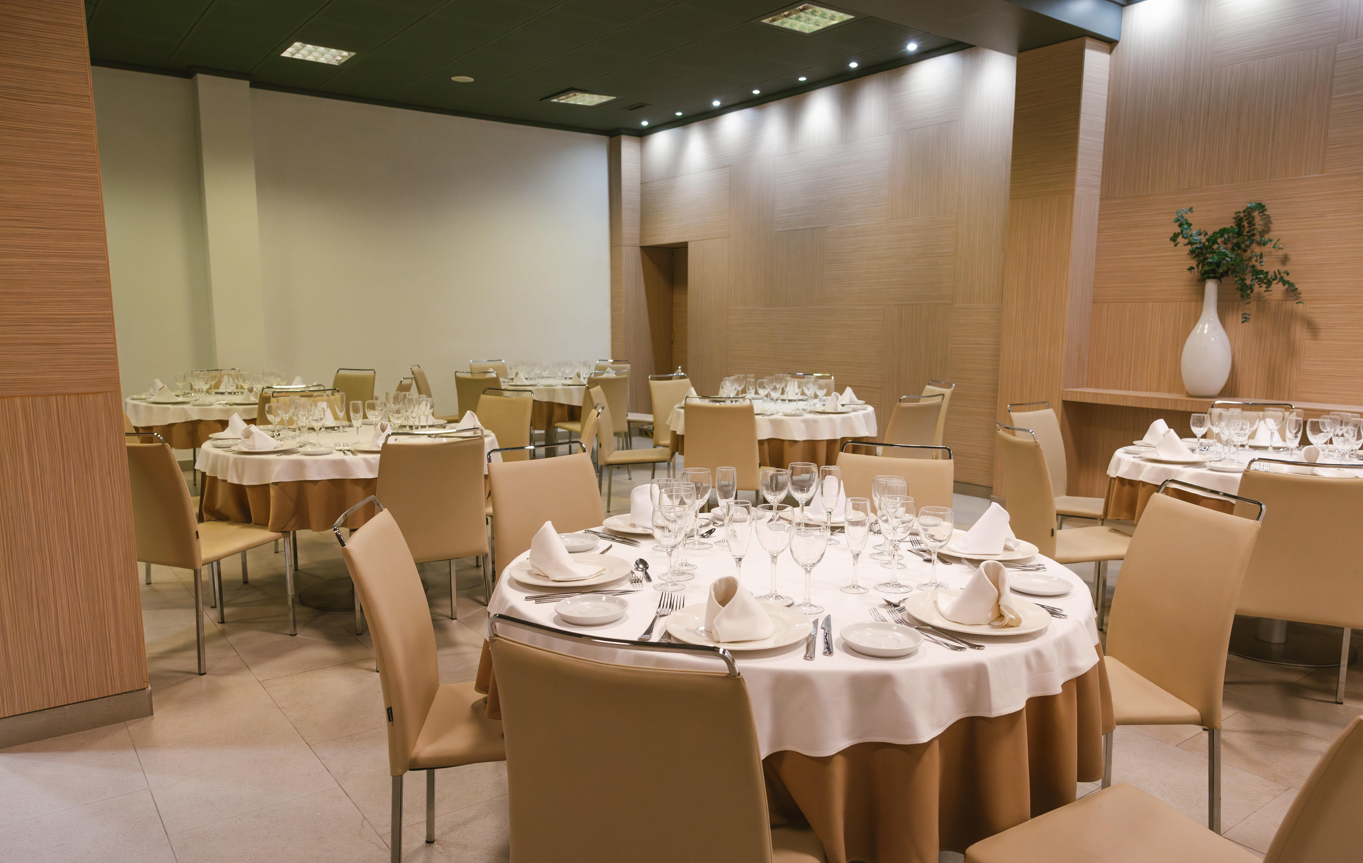 una habitación llena de mesas y sillas con platos y copas de vino